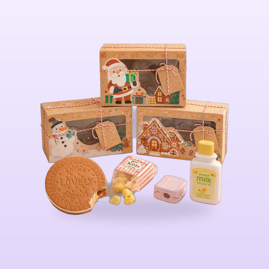 Desk snack gift set with a biscuit memo pad, popcorn erasers, sharpener, milk correction tape and three Christmas boxes, on a lilac background