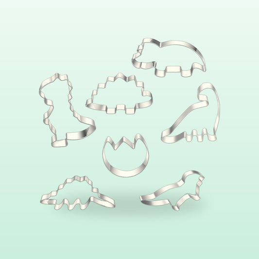 Seven stainless steel dinosaur cookie cutters laid out together, on a mint background
