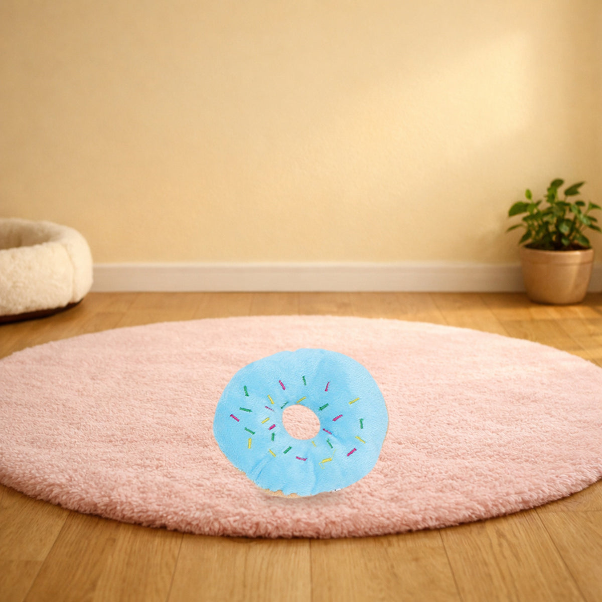 Blue plush donut squeaky pet toy on a pink rug in a living room