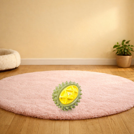 Green durian squeaky dog chew toy on a soft pink rug