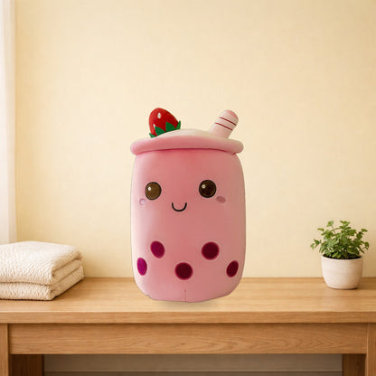 Strawberry milk tea plush pillow sitting on a light oak bench