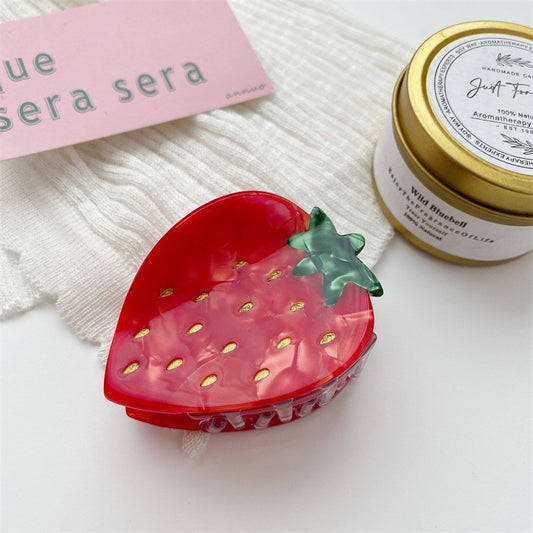 Single red translucent strawberry-shaped hair claw clip with green leaf top and gold seed accents.