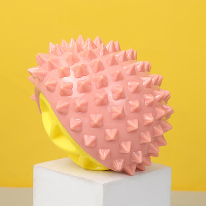 One pink spiky rubber chew toy with a yellow hollow base on a white pedestal against a yellow background.
