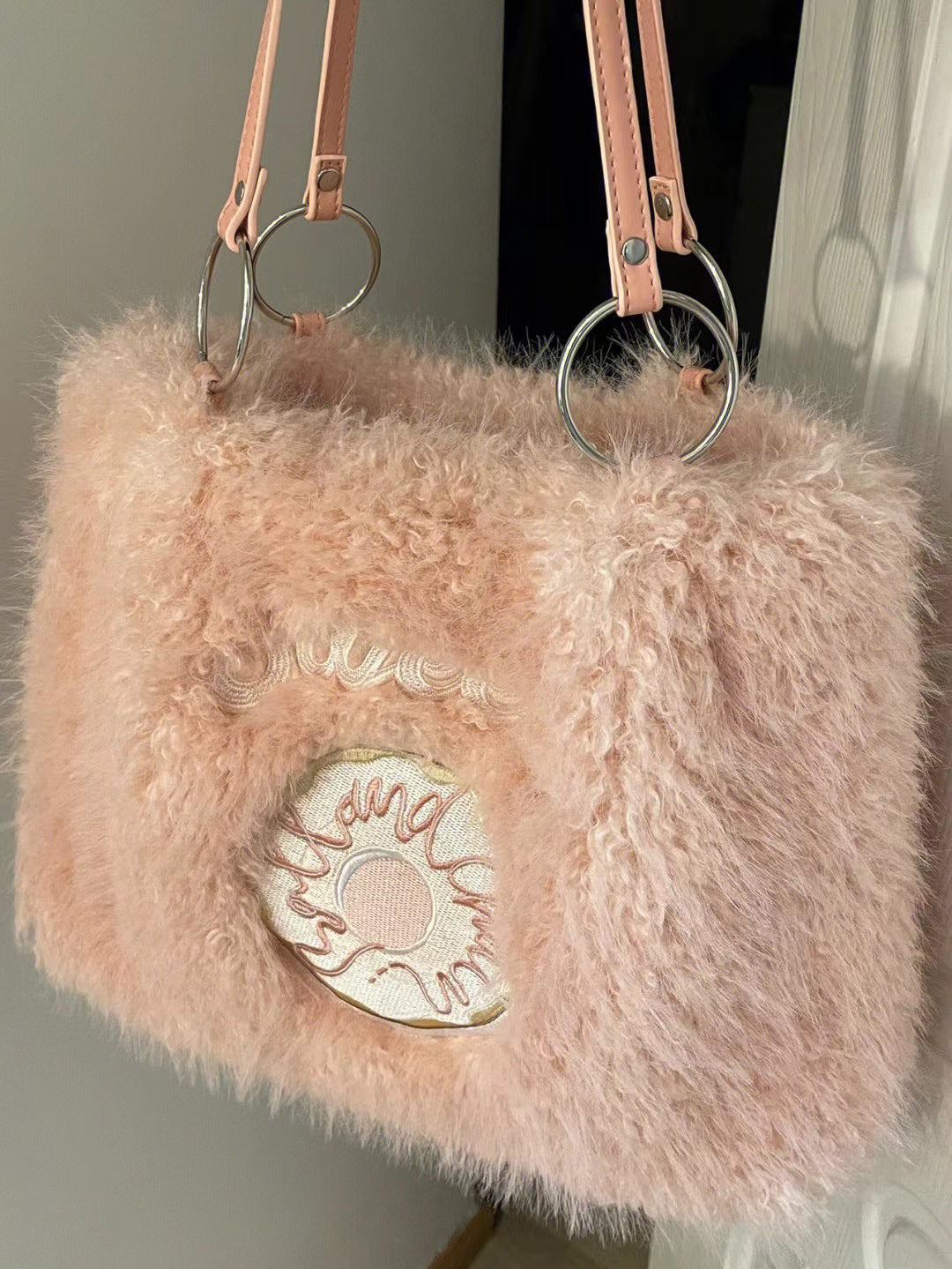 Pink plush tote bag with a fluffy texture, featuring a donut embroidery on the front and silver ring handles.