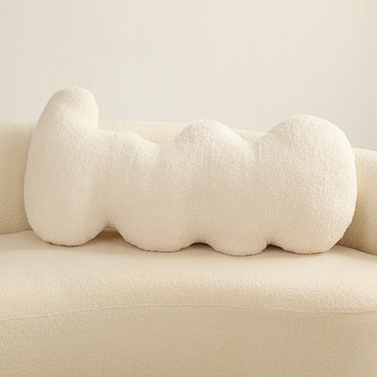 Single cream boucle-textured elongated pillow with five rounded connected lobes on a sofa.
