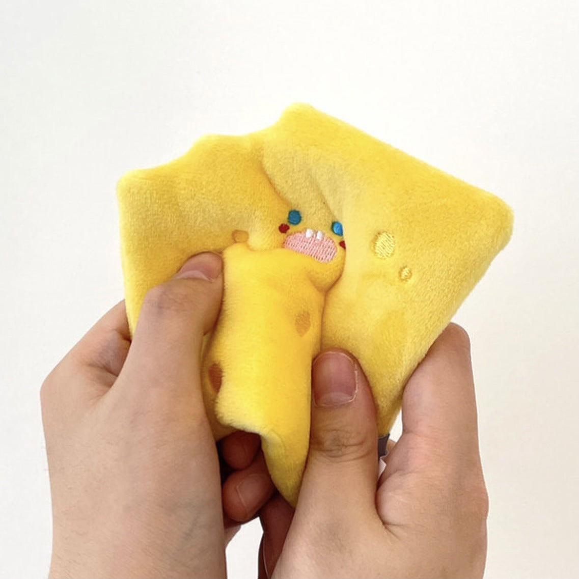 Cheese wedge crinkle dog toy in vibrant yellow, being squeezed, featuring a playful face and cute detailing.