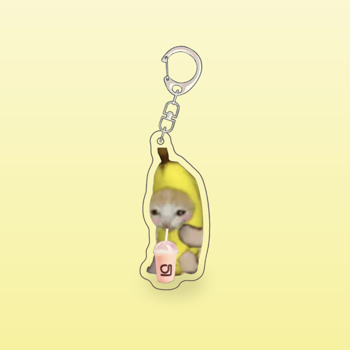 Banana cat meme acrylic keychain with a pink drink and a silver clip, on a butter yellow background