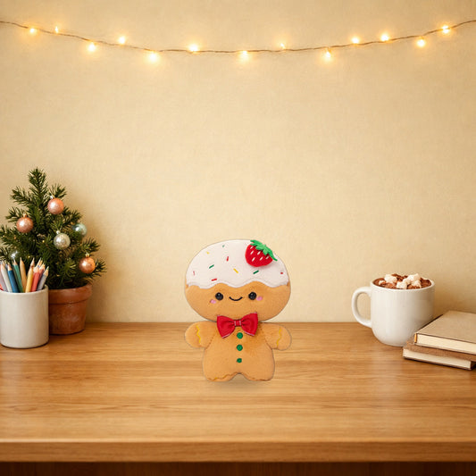 Strawberry frosted gingerbread plush on a festive wooden desk