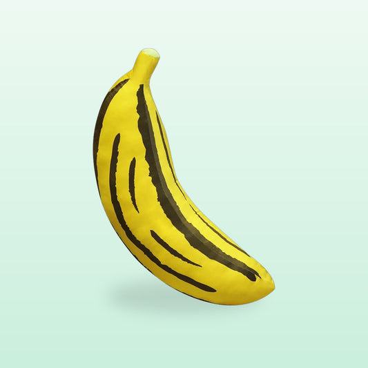 Giant yellow banana plush cushion with dark stripes, on a soft mint background