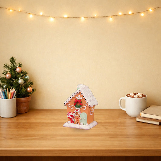 Gingerbread house Christmas ornament on a festive wooden desk