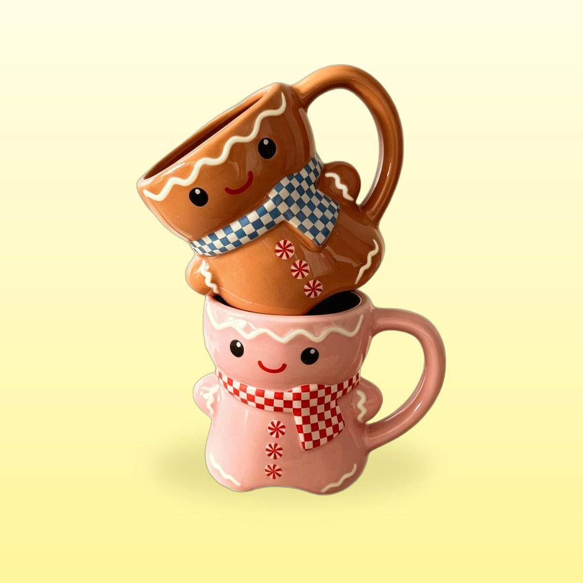 Pink and classic brown gingerbread man mugs stacked on a butter yellow background