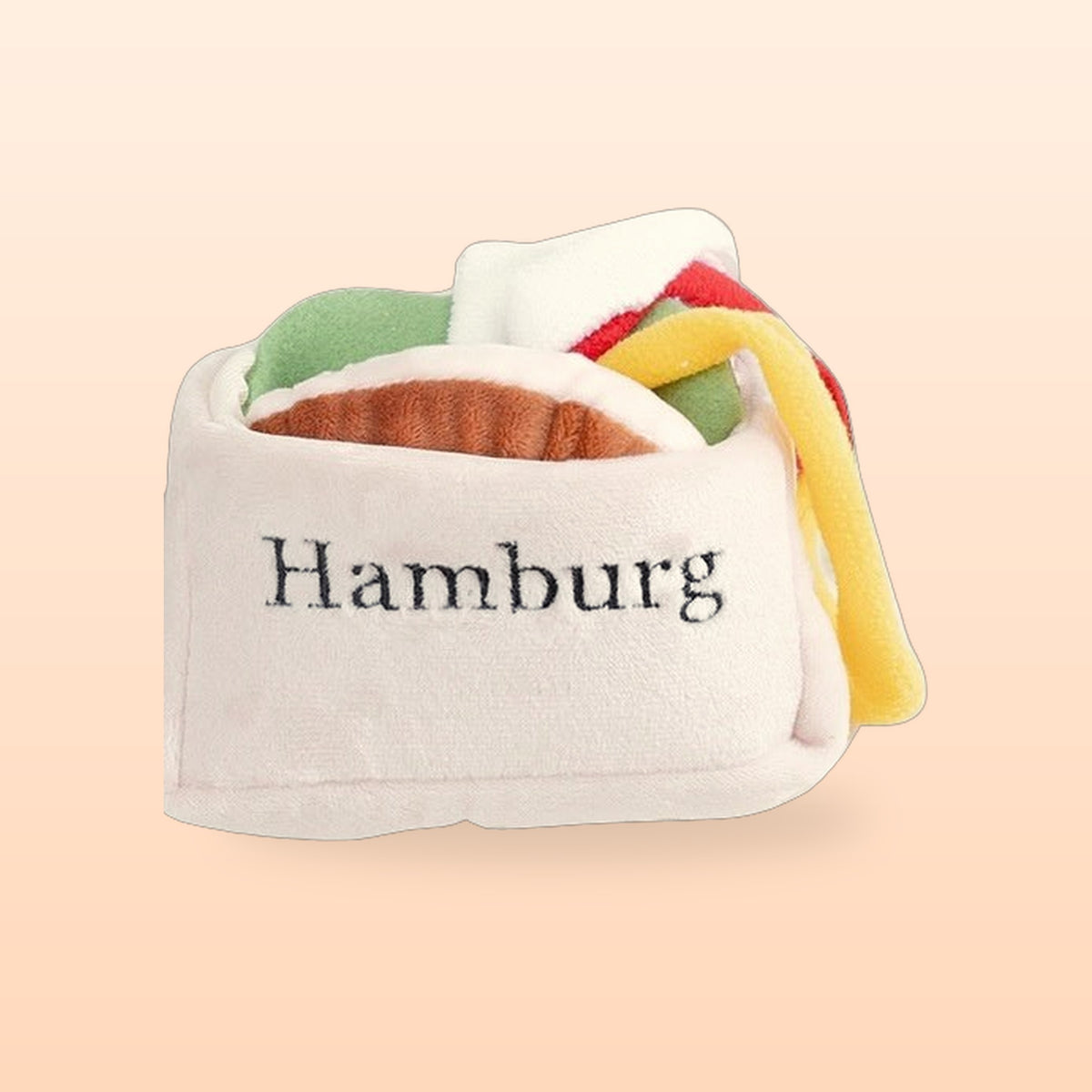 Burger snuffle pet toy with plush fillings tucked in its bun, on a peach background