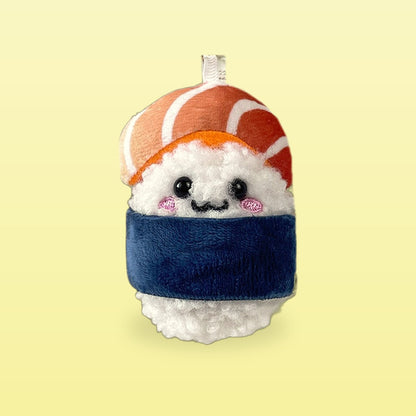 Salmon sushi plush keychain with a blue nori band on a butter yellow background
