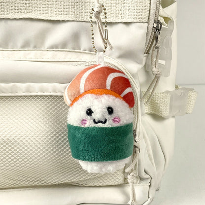 Green nori salmon sushi plush charm hanging on a ball chain from a cream backpack