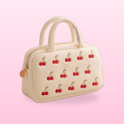 Cream cherry embroidered vanity bag with twin handles on a pink background