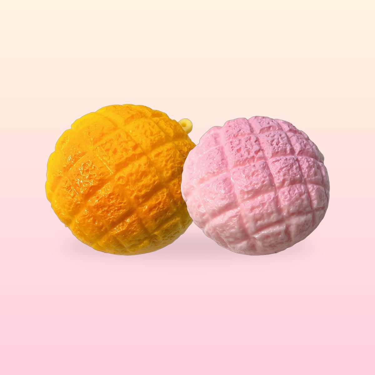 Golden and strawberry pink pineapple bun squishies with a crackly bakery top on a cream and pink background