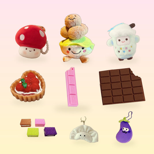 A mix of food-shaped plush charms, erasers and desk snacks on a pink and butter yellow background