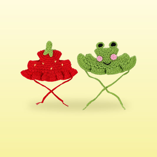 Red strawberry and green frog crochet cat hats with tie strings on a butter yellow background