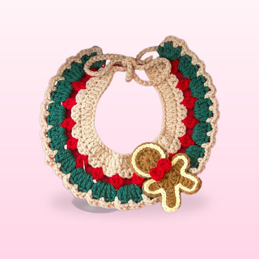 Crochet Christmas pet collar in green, red and beige with a gingerbread man on a soft pink background