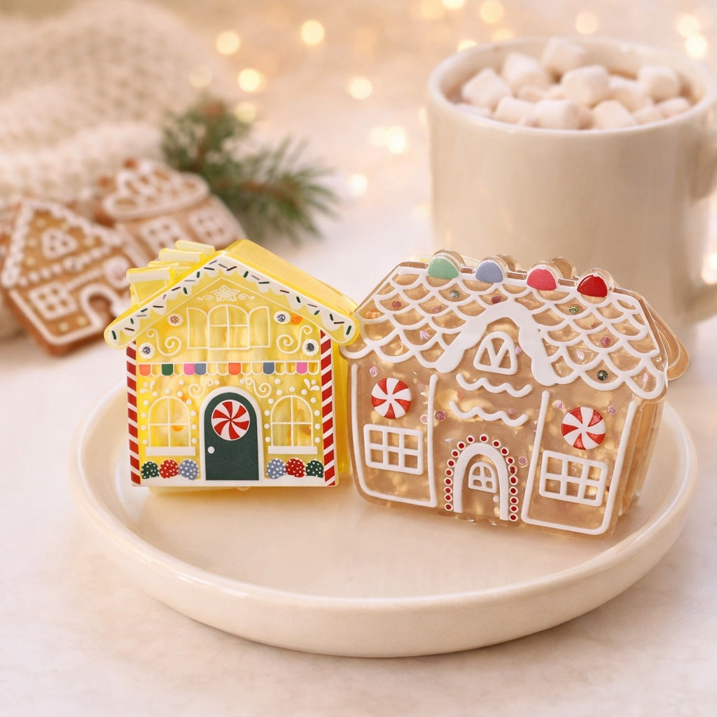 Gingerbread house claw clips on a cream dish beside a mug of hot chocolate with marshmallows