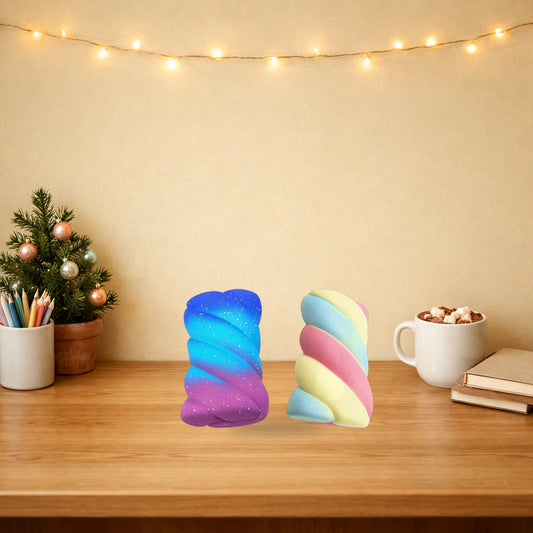 Starry Sky and Rainbow marshmallow squishies standing on a wooden desk beside a mini Christmas tree and hot chocolate