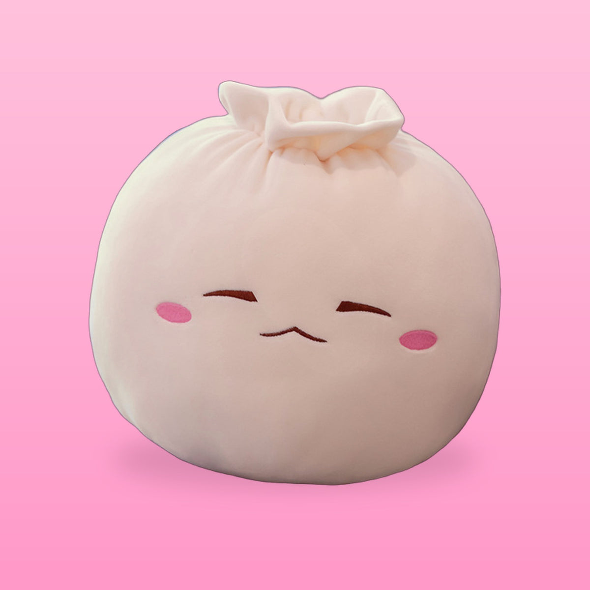 Cream bao bun plush pillow with sleepy closed eyes and pink cheeks on a pink background
