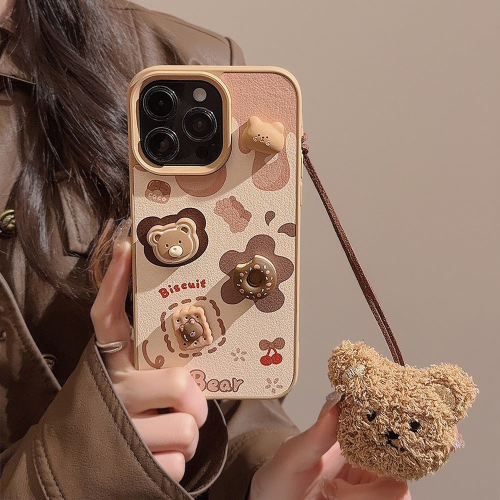 Hand holding the biscuit bear iPhone case with its fluffy plush bear charm dangling from the cord