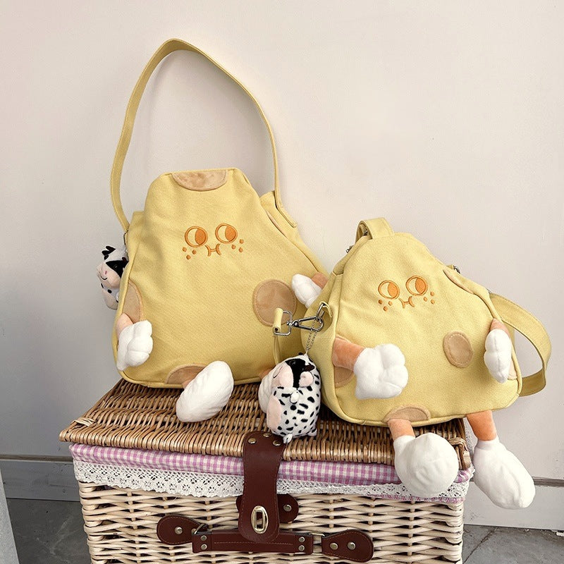 Cheese tote and the smaller cheese crossbody bag side by side on a picnic basket