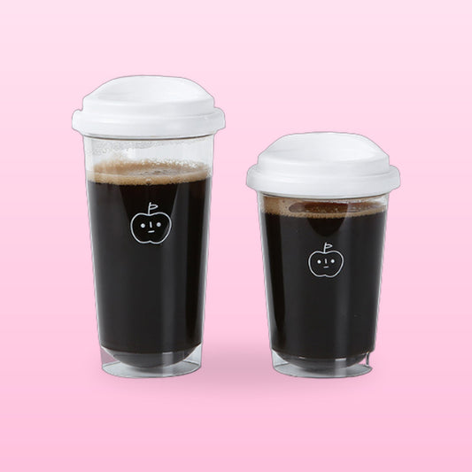 Apple face glass cups with white lids in 470 ml and 350 ml sizes, on a pink background