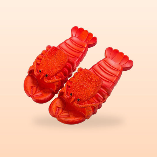 Pair of red lobster slippers with claw toes, on a peach background