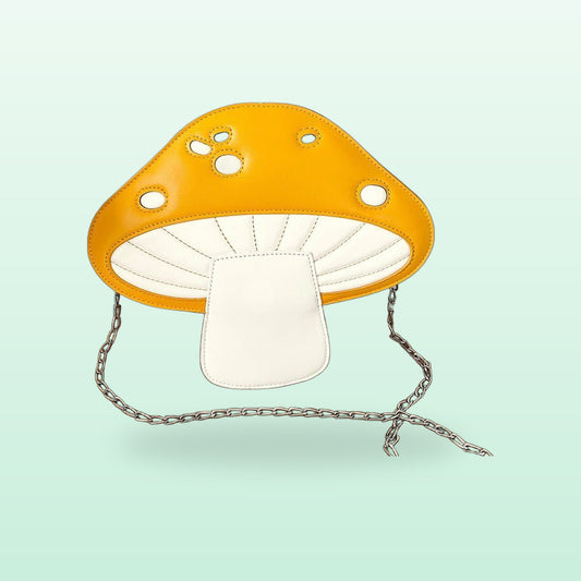 Yellow mushroom crossbody bag with white spots and a silver chain strap on a mint background