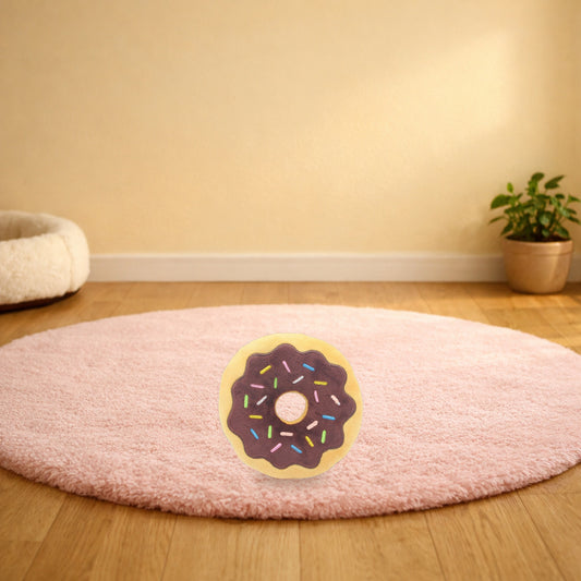 Chocolate donut squeaky plush pet toy on a pink rug in a living room