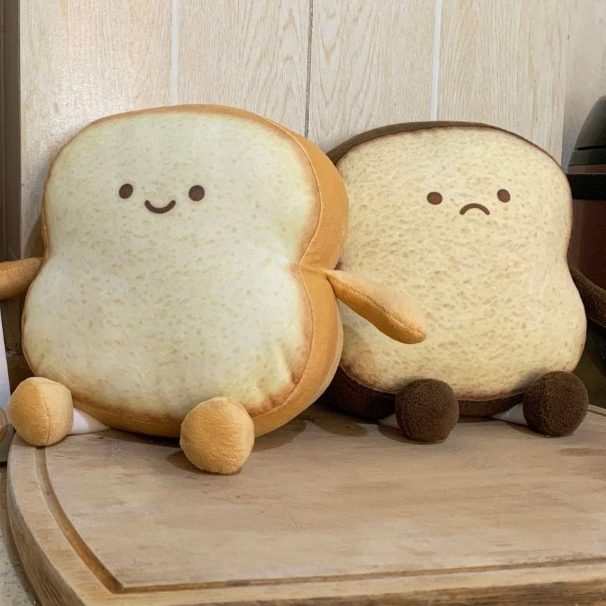 Happy and sad toast slice plushies on a wooden bread board