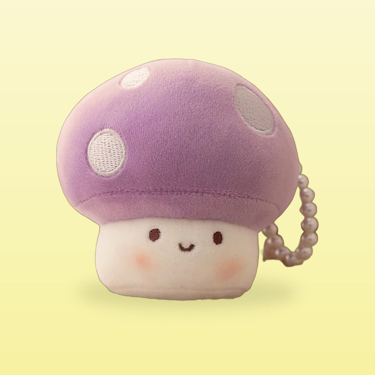 Purple mushroom plush keychain with white spots and a happy face