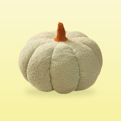 Teddy pumpkin plush cushion, sage green with a brown stem, on a butter yellow background