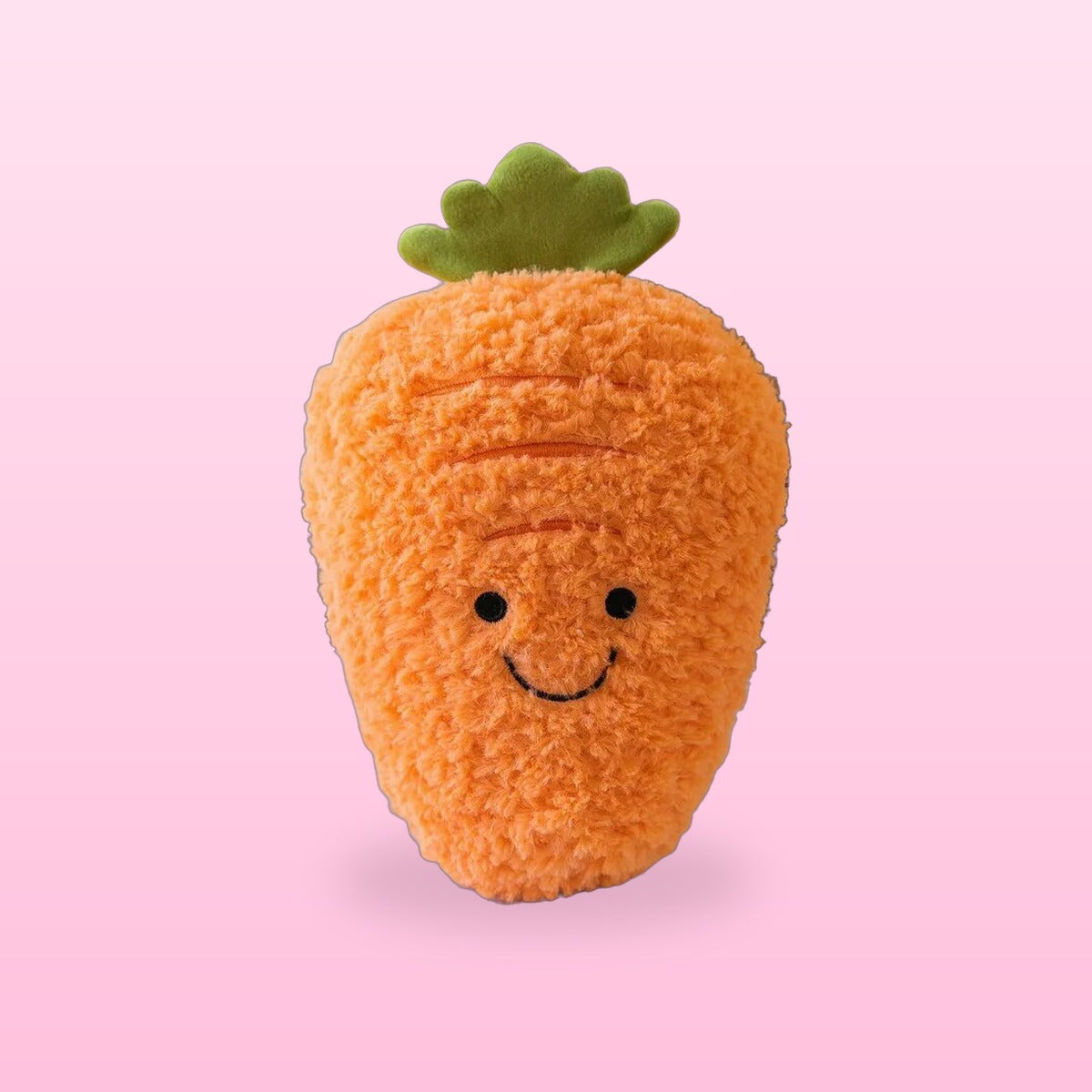Fluffy orange carrot plush with a green top and a smiling face, on a bubblegum pink background