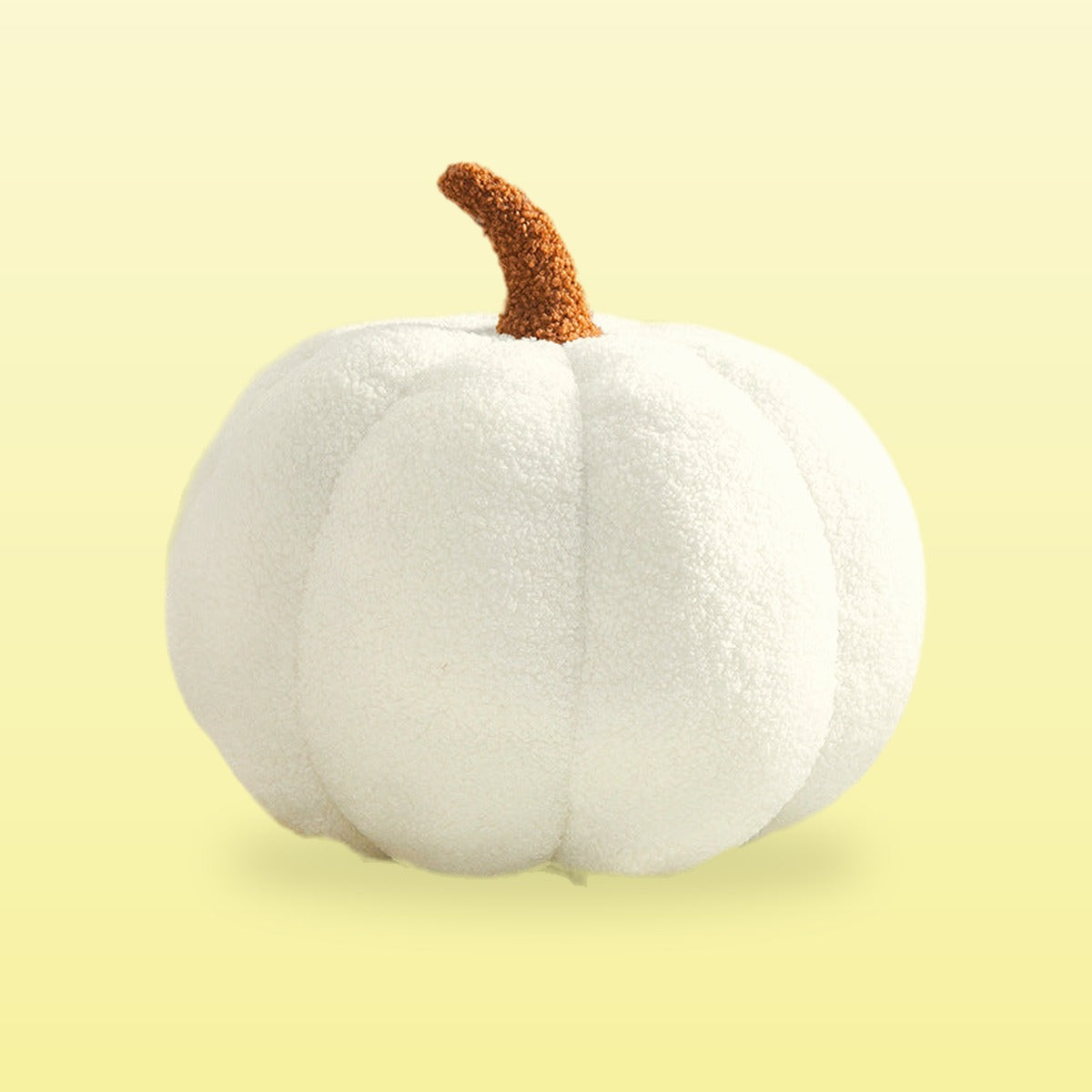 Teddy pumpkin plush cushion, cream with a brown stem, on a butter yellow background