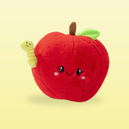 Red apple plush with a smiling face and a little green worm, on a butter yellow background