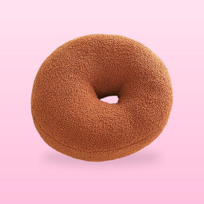Sweet donut cushion in warm brown boucle with a centre hole, on a bubblegum pink background