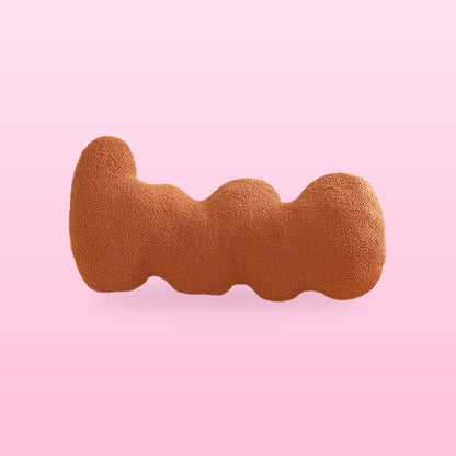 Chocolate brown wavy bolster cushion with rounded lobes, on a bubblegum pink background