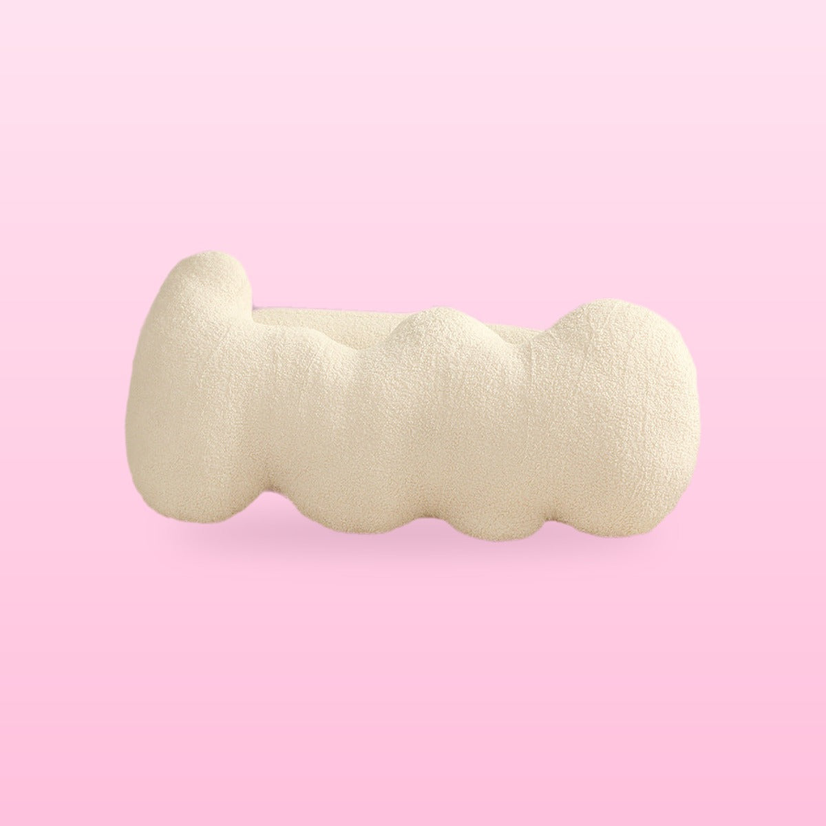 Beige wavy bolster cushion in cream boucle with rounded lobes, on a bubblegum pink background