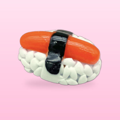 Salmon nigiri miniature food fridge magnet with a seaweed band, on a pink background