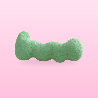 Green wavy bolster cushion with rounded lobes, on a bubblegum pink background