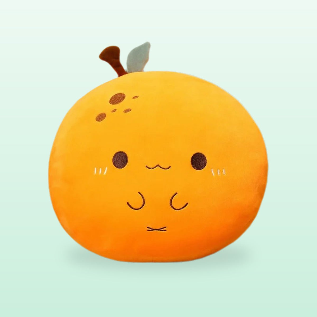 Orange plush pillow with a leaf and a happy face, on a mint background