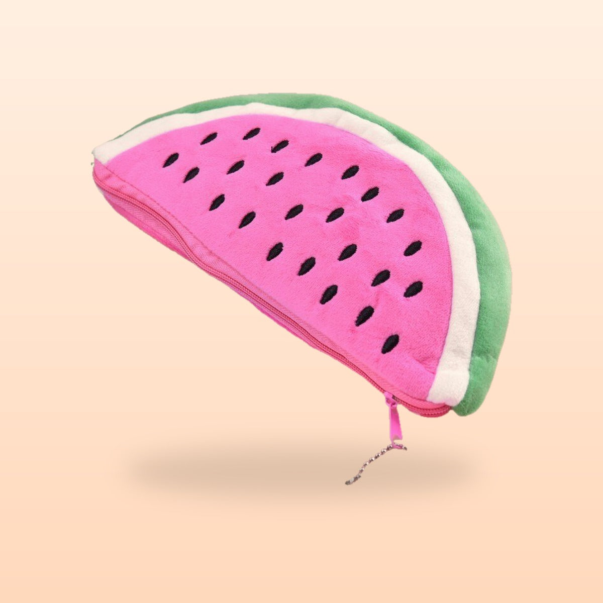 Pink watermelon plush pencil case with black seeds and a green rind, on a soft peach background