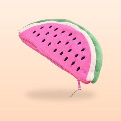 Pink watermelon plush pencil case with black seeds and a green rind, on a soft peach background