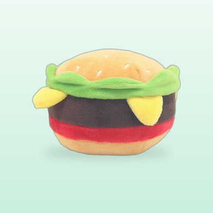 Burger plush pet toy with a sesame bun, lettuce, patty and cheese, on a mint background