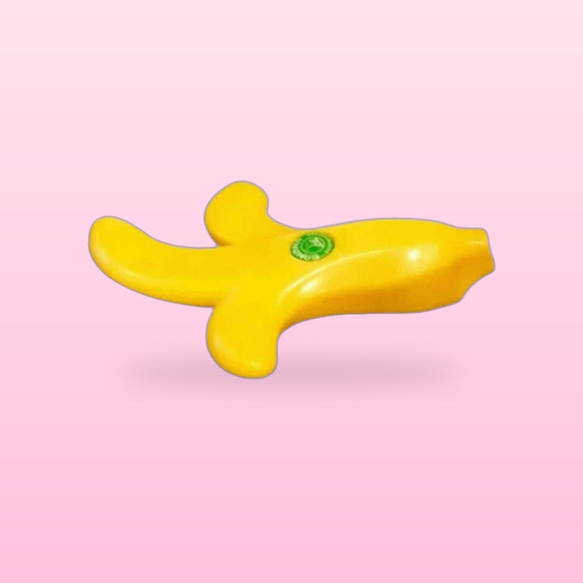 Yellow peeled banana door stopper lying on its side, on a pastel pink background