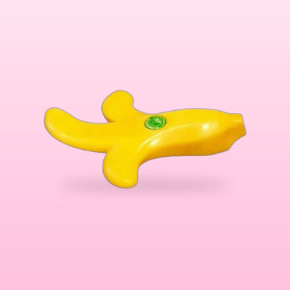 Yellow peeled banana door stopper lying on its side, on a pastel pink background