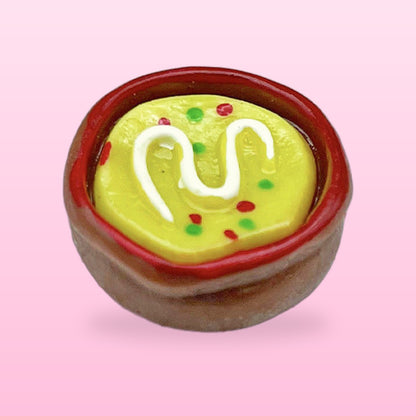 Soup bowl miniature food fridge magnet with a yellow filling and cream swirl, on a pink background